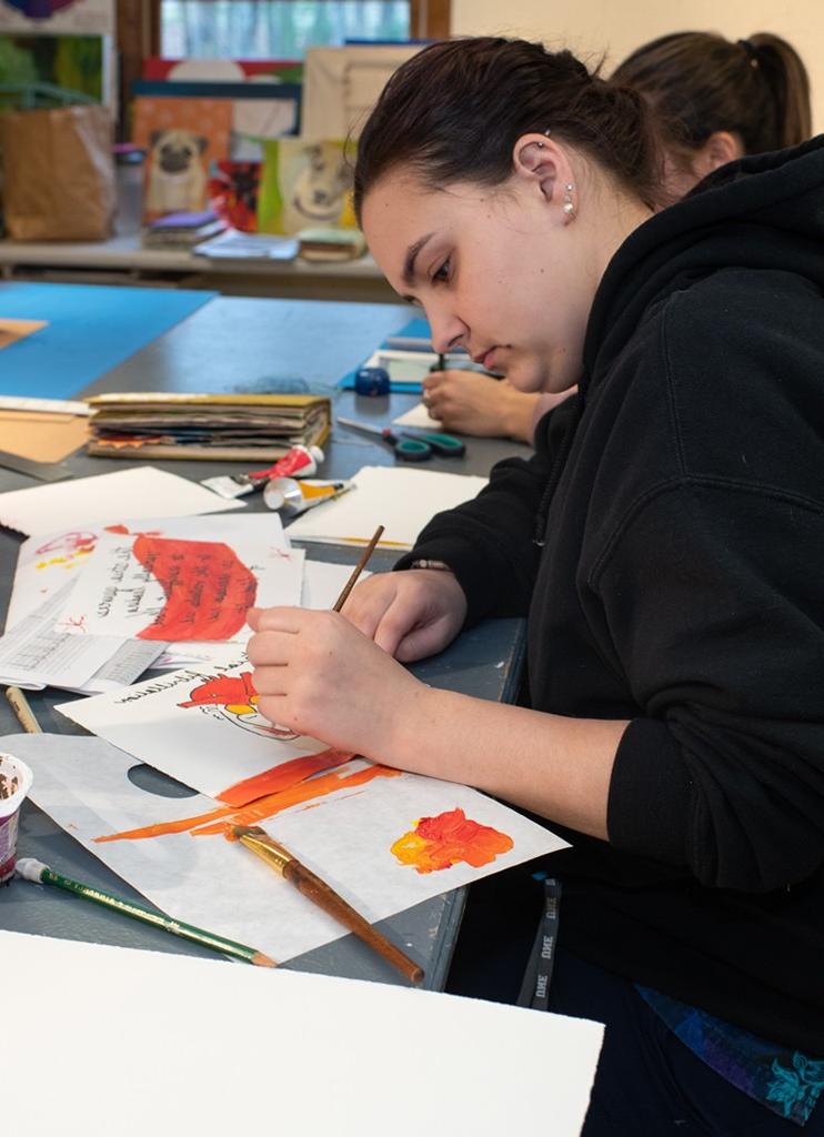 A student watercolors pages as part of a bookmaking project