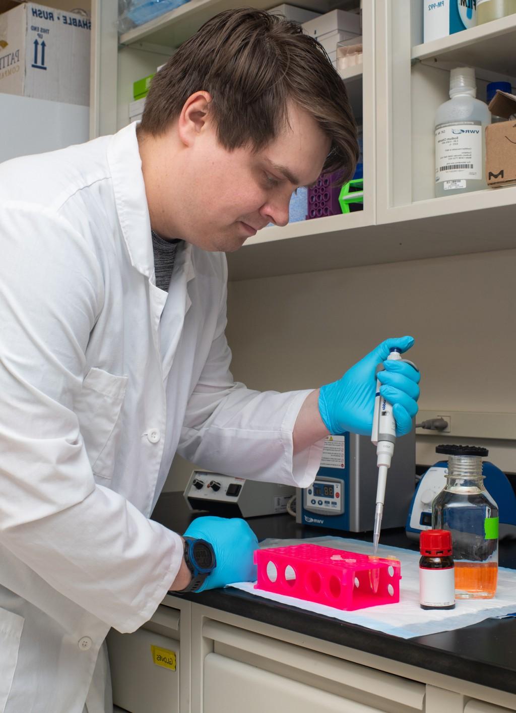 A student pipes a liquid into a container in a research lab