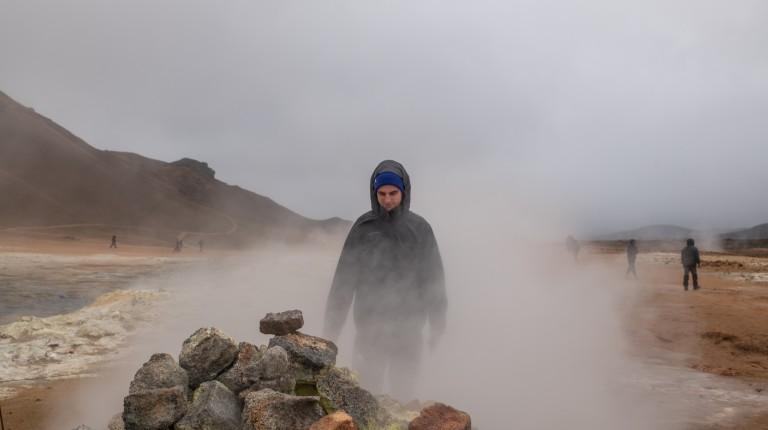 A student walks through dense fog on a rocky landscape