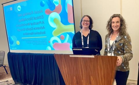 Pamela Bruno (left) and Colleen Fuller from UNE's Center from Excellence in Public Health pose for a photo next to a slideshow presentation displayed on a screen